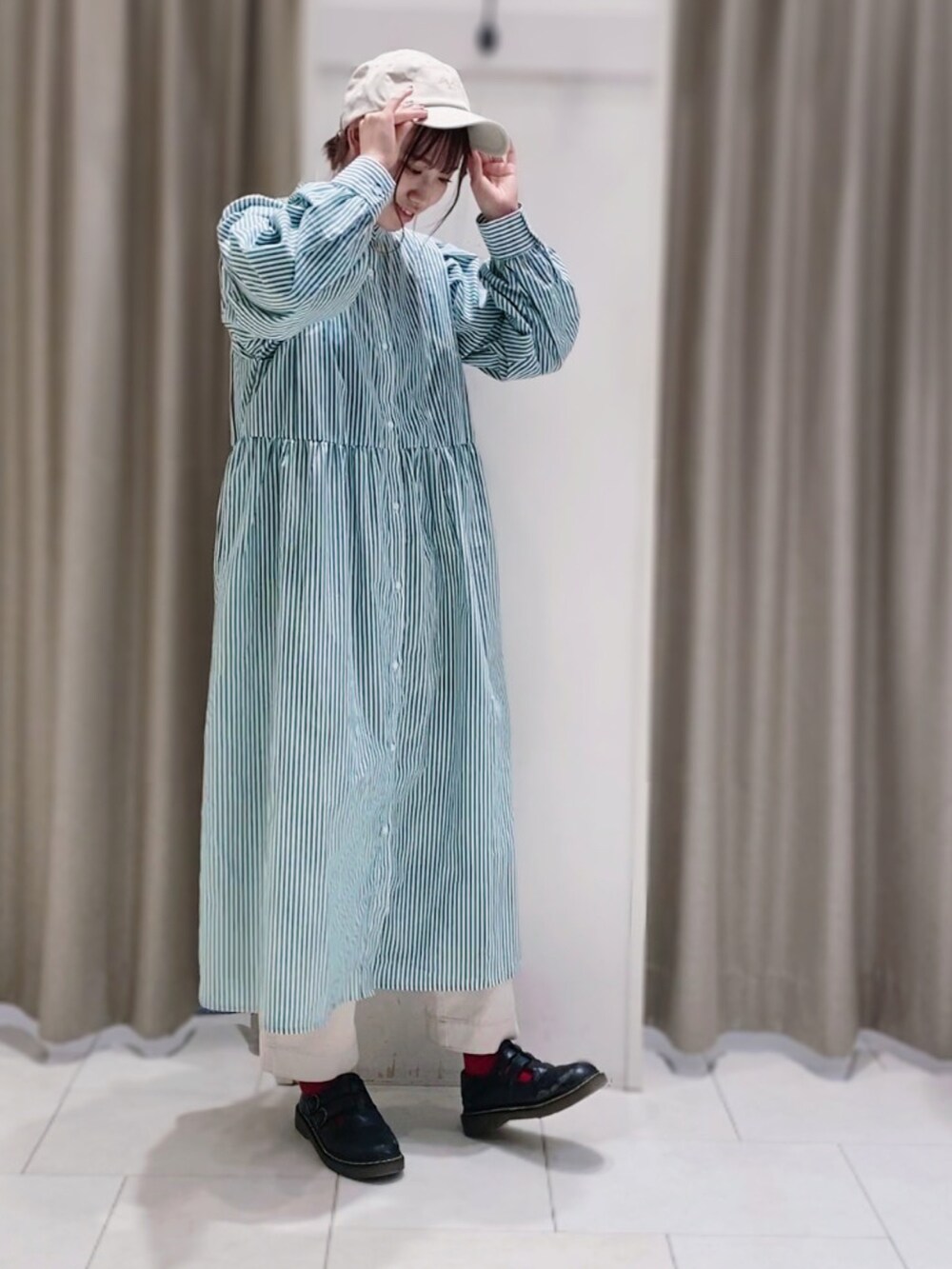 グリーン系のワンピース、ホワイト系のデニムパンツ、ホワイト系の帽子を着用したレディースの冬コーディネートの2枚目の写真