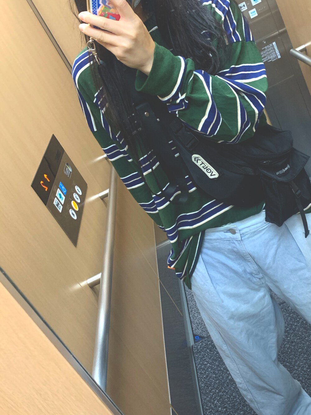 グリーン系のTシャツ/カットソー、ブルー系のデニムパンツ、ブラック系のキャップを着用したレディースの秋コーディネートの2枚目の写真