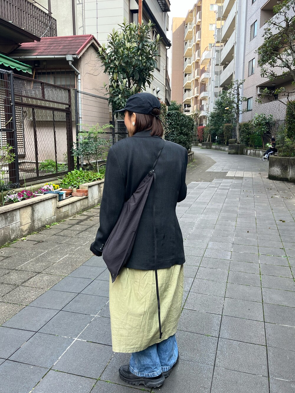 グレー系のジャケット/アウター、グリーン系のワンピース/ドレス、ブラック系のスニーカーを着用したレディースの春コーディネートの2枚目の写真
