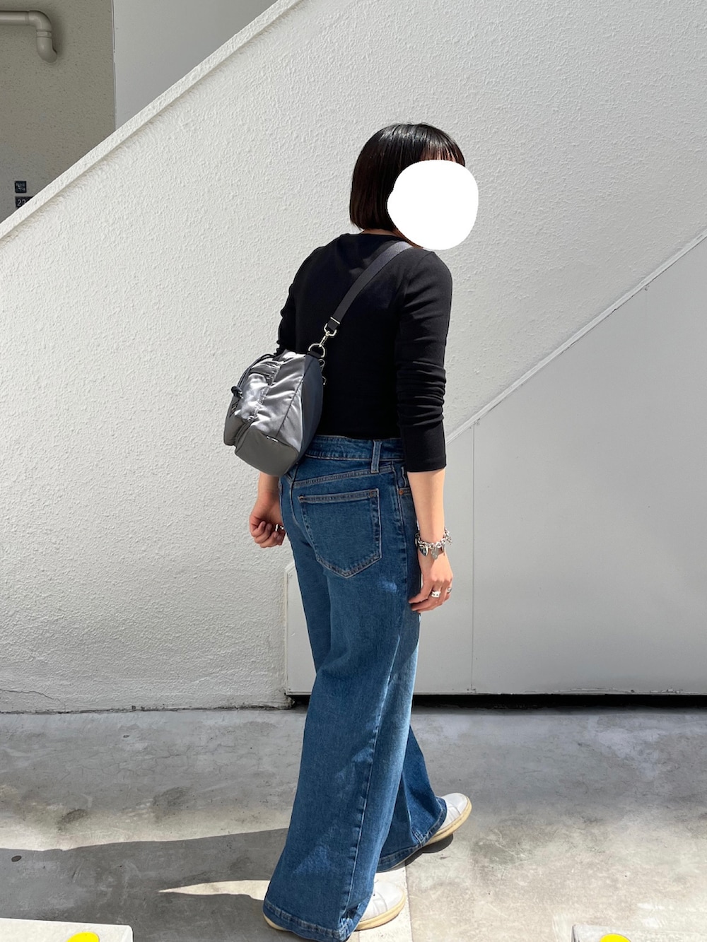 ブラック系のTシャツ/カットソー、ブルー系のデニムパンツ、ホワイト系のスニーカーを着用したレディースの春コーディネートの2枚目の写真