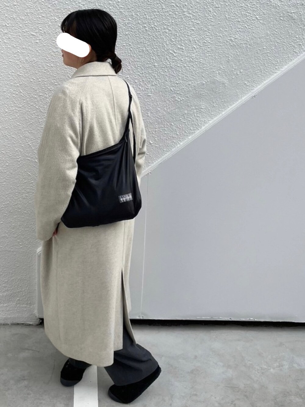 グレー系のパンツ、ブラック系のスニーカー、グレー系のステンカラーコートを着用したレディースの冬コーディネートの2枚目の写真