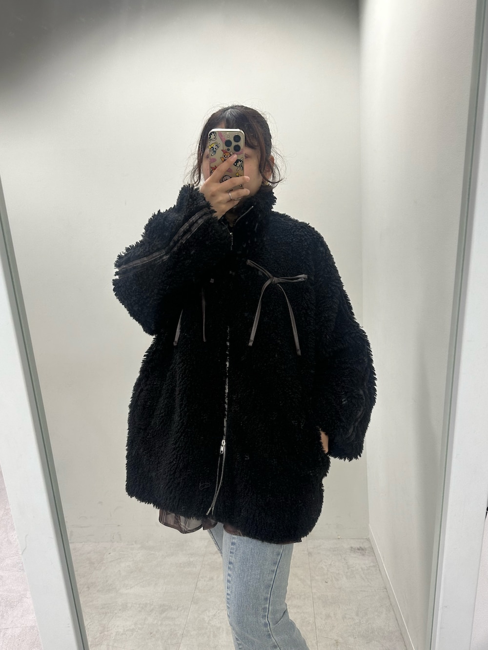 ブラック系のブルゾン、ブルー系のデニムパンツ、ホワイト系のスニーカーを着用したレディースの秋コーディネートの2枚目の写真