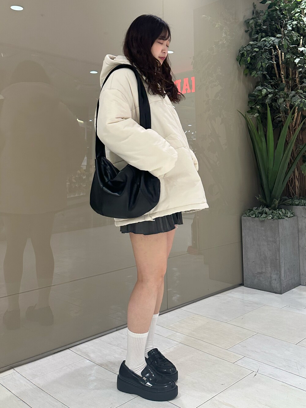 ブラック系のローファー、グレー系のスカート、ホワイト系のダウンジャケット/コートを着用したレディースの冬コーディネートの2枚目の写真