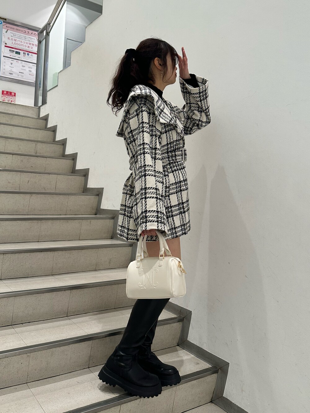 ブラック系のブーツ、その他のその他アウター、ホワイト系のハンドバッグを着用したレディースの秋コーディネートの3枚目の写真