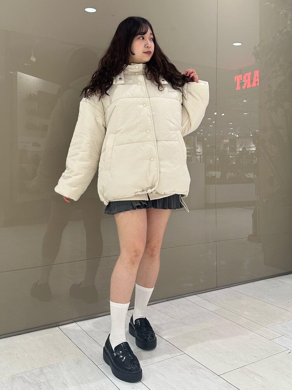 ブラック系のローファー、グレー系のスカート、ホワイト系のダウンジャケット/コートを着用したレディースの冬コーディネートの3枚目の写真