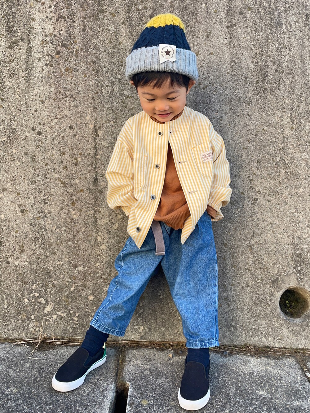 イエロー系のノーカラージャケット、イエロー系のニット/セーター、ブルー系のその他パンツを着用したキッズの秋コーディネートの2枚目の写真