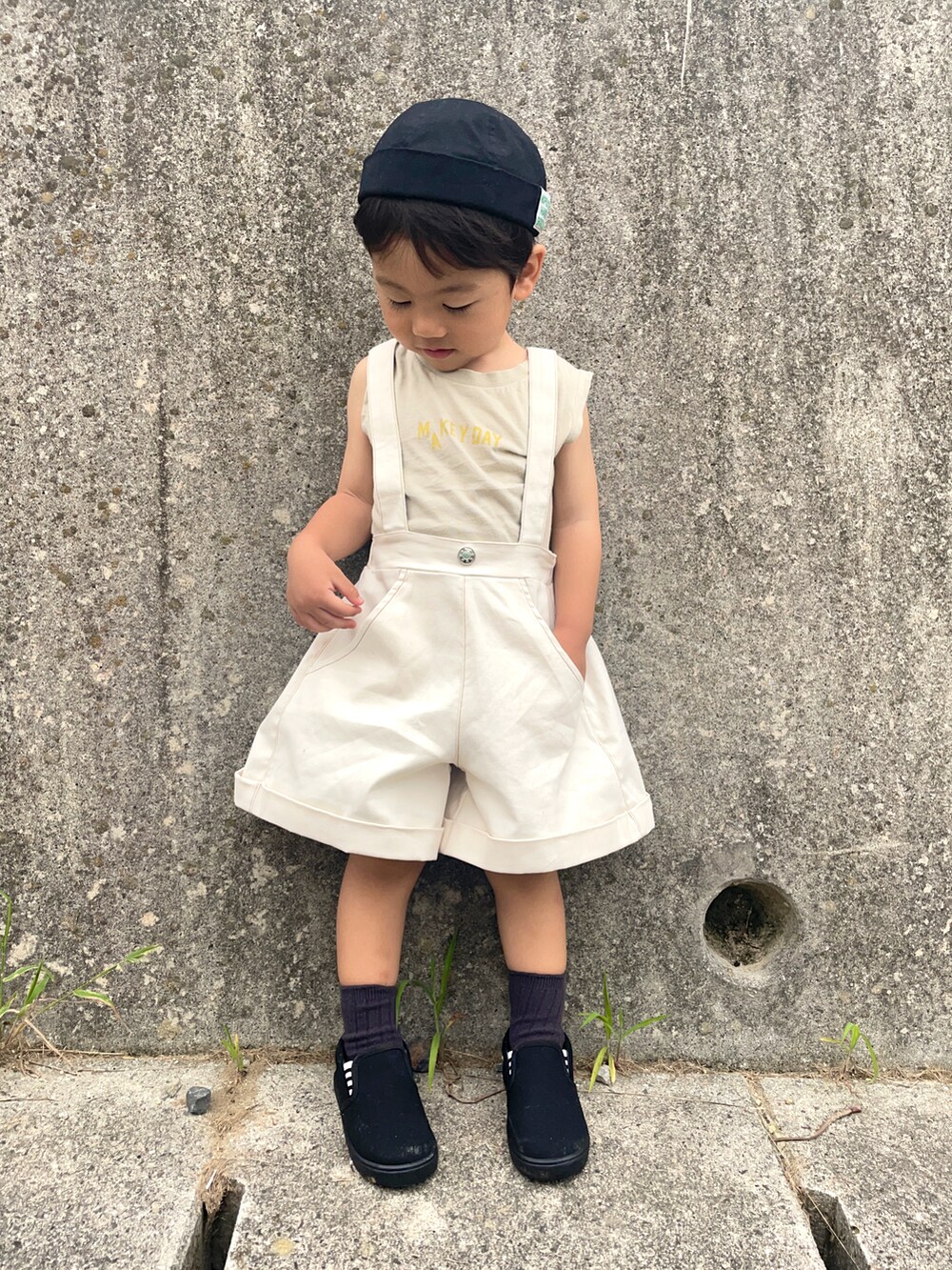 ベージュ系のタンクトップ、ブラック系のスリッポン、ブラック系のキャップを着用したキッズの夏コーディネートの3枚目の写真