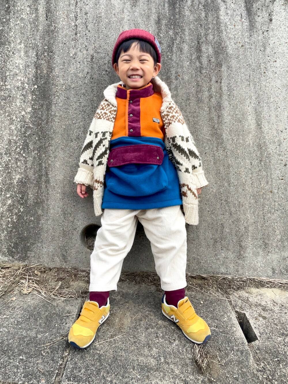 オレンジ系のスウェット、ホワイト系のカーディガン/ボレロ、ホワイト系のパンツを着用したキッズの冬コーディネートの2枚目の写真