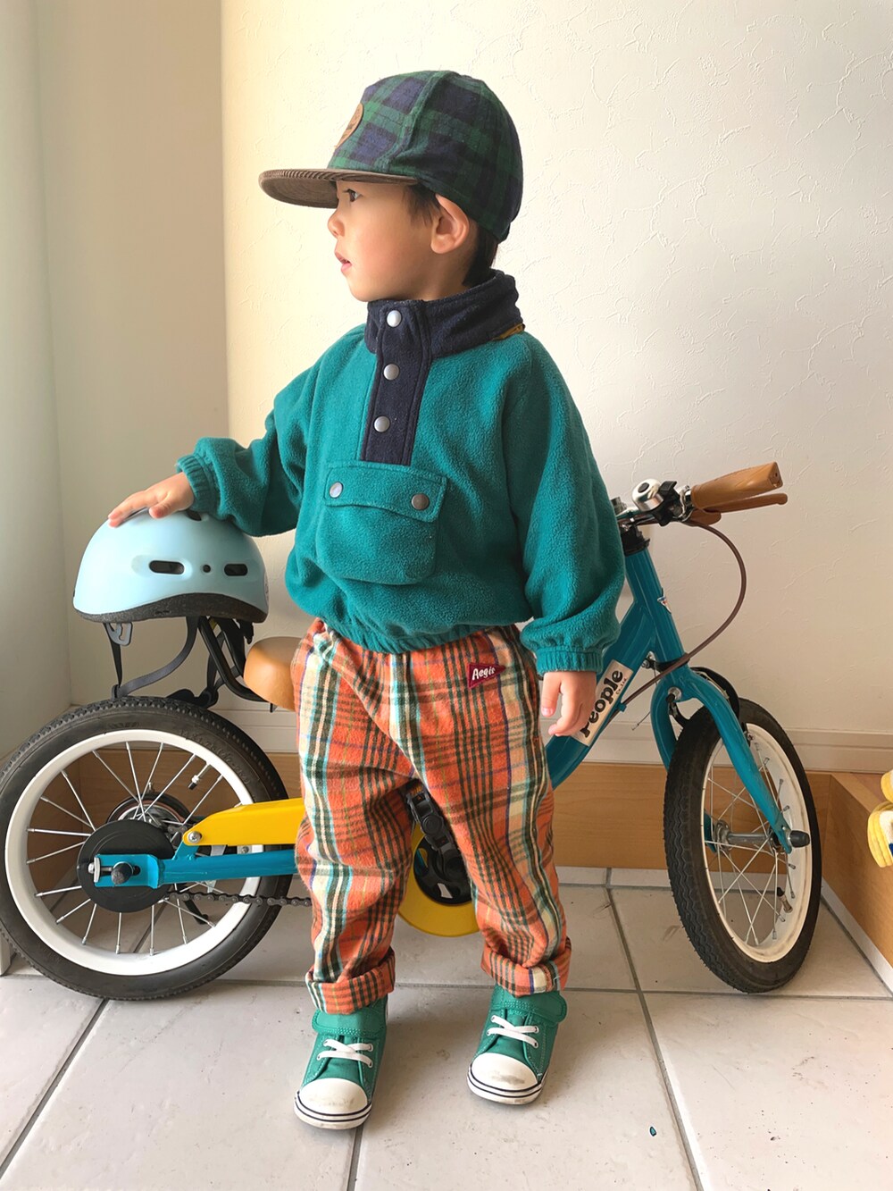 グリーン系のマウンテンパーカー、オレンジ系のその他パンツ、グリーン系のスニーカーを着用したキッズの冬コーディネートの2枚目の写真