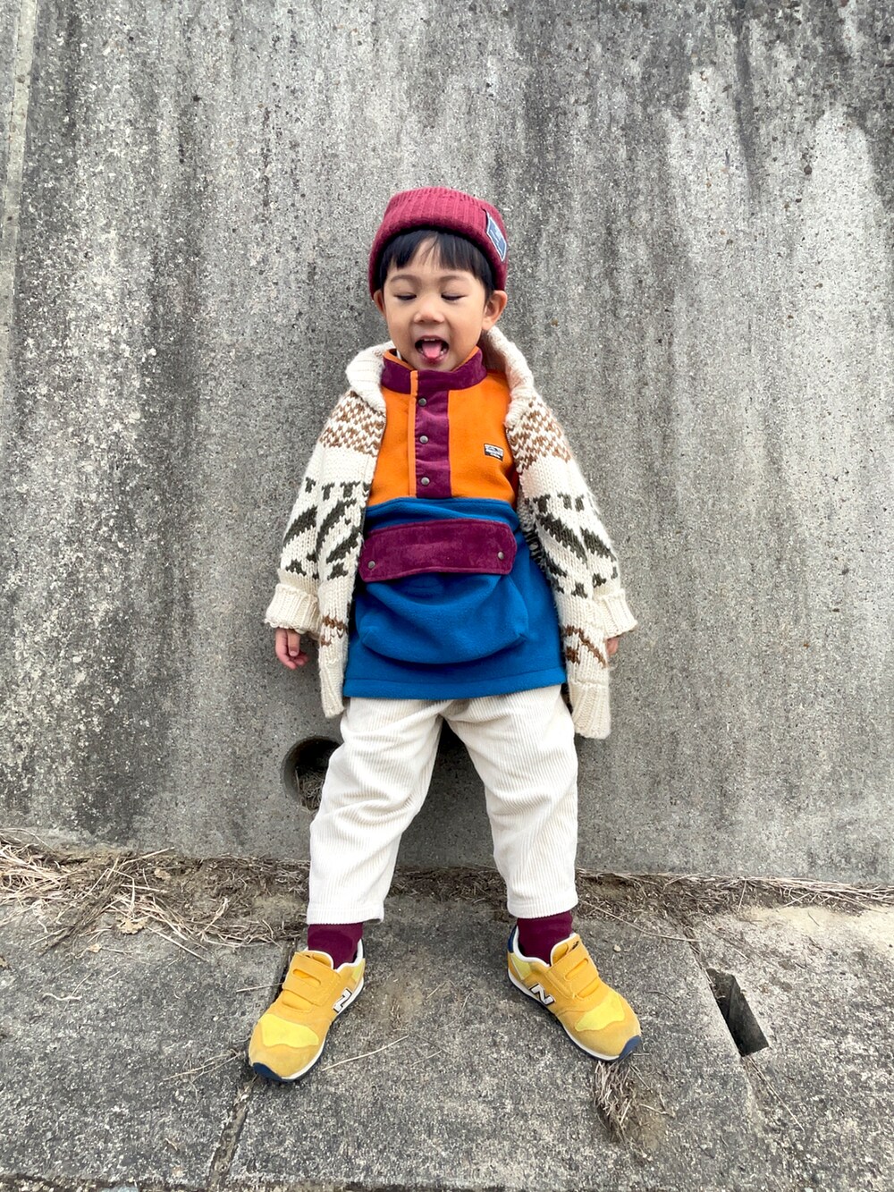オレンジ系のスウェット、ホワイト系のカーディガン/ボレロ、ホワイト系のパンツを着用したキッズの冬コーディネートの3枚目の写真