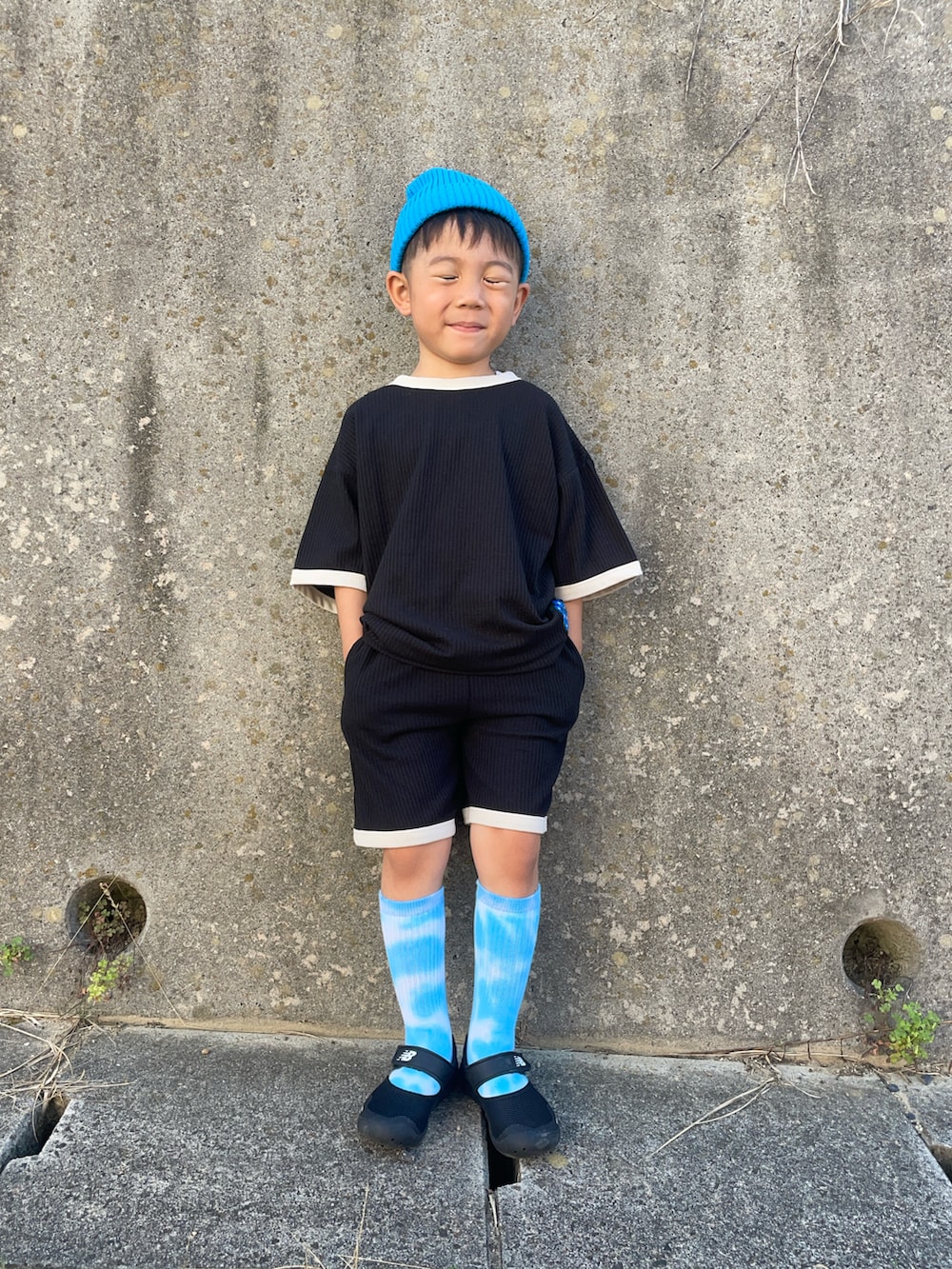 ブラック系のセットアップ、ブラック系のスニーカー、ブルー系のニットキャップ/ビーニーを着用したキッズの夏コーディネートの2枚目の写真