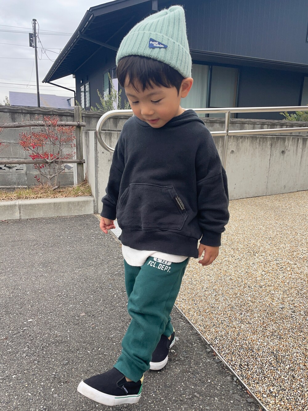 ブラック系のパーカー、ホワイト系のブルゾン、グリーン系のスウェットパンツを着用したキッズの秋コーディネートの4枚目の写真