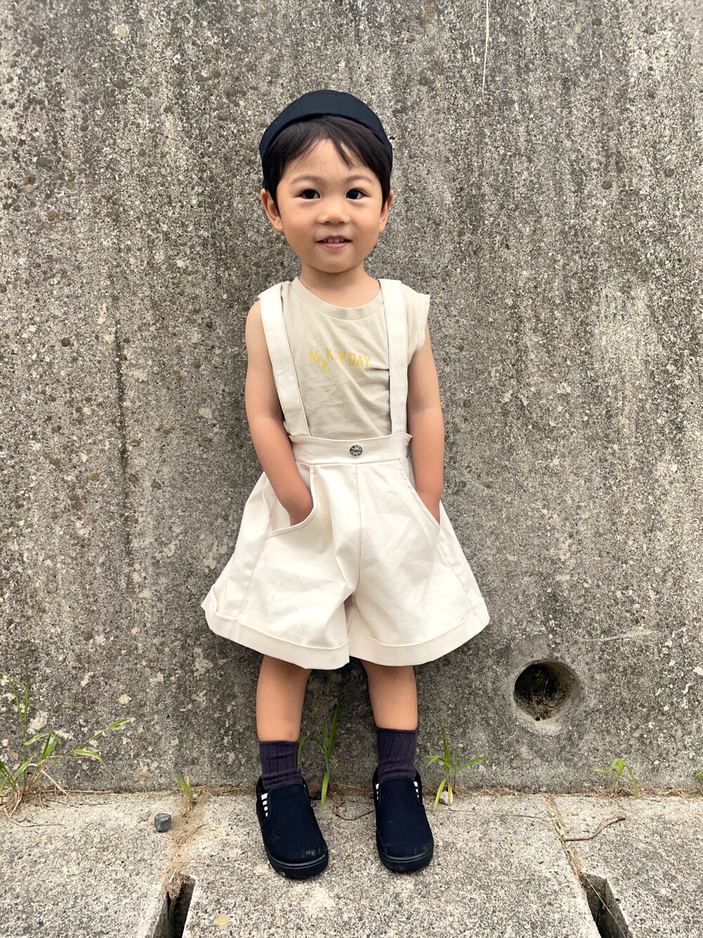 ベージュ系のタンクトップ、ブラック系のスリッポン、ブラック系のキャップを着用したキッズの夏コーディネートの2枚目の写真