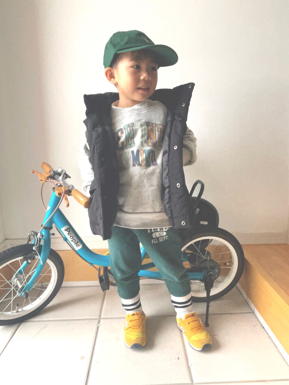 グレー系のスウェット、ブラック系のダウンベスト、グリーン系のスウェットパンツを着用したキッズの秋コーディネートの2枚目の写真