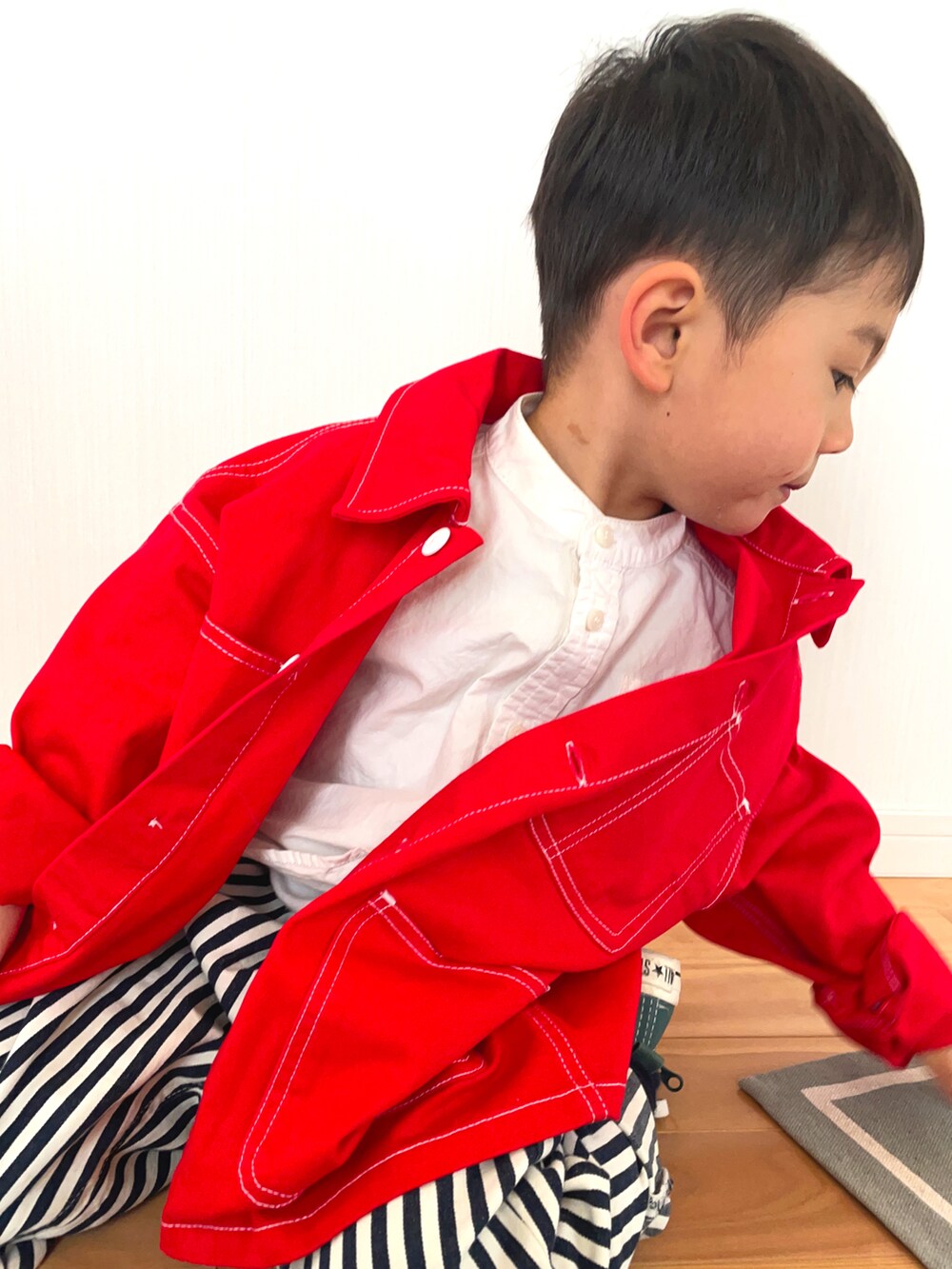 レッド系のブルゾン、ホワイト系のシャツ/ブラウス、その他のデニムパンツを着用したキッズの春コーディネートの2枚目の写真