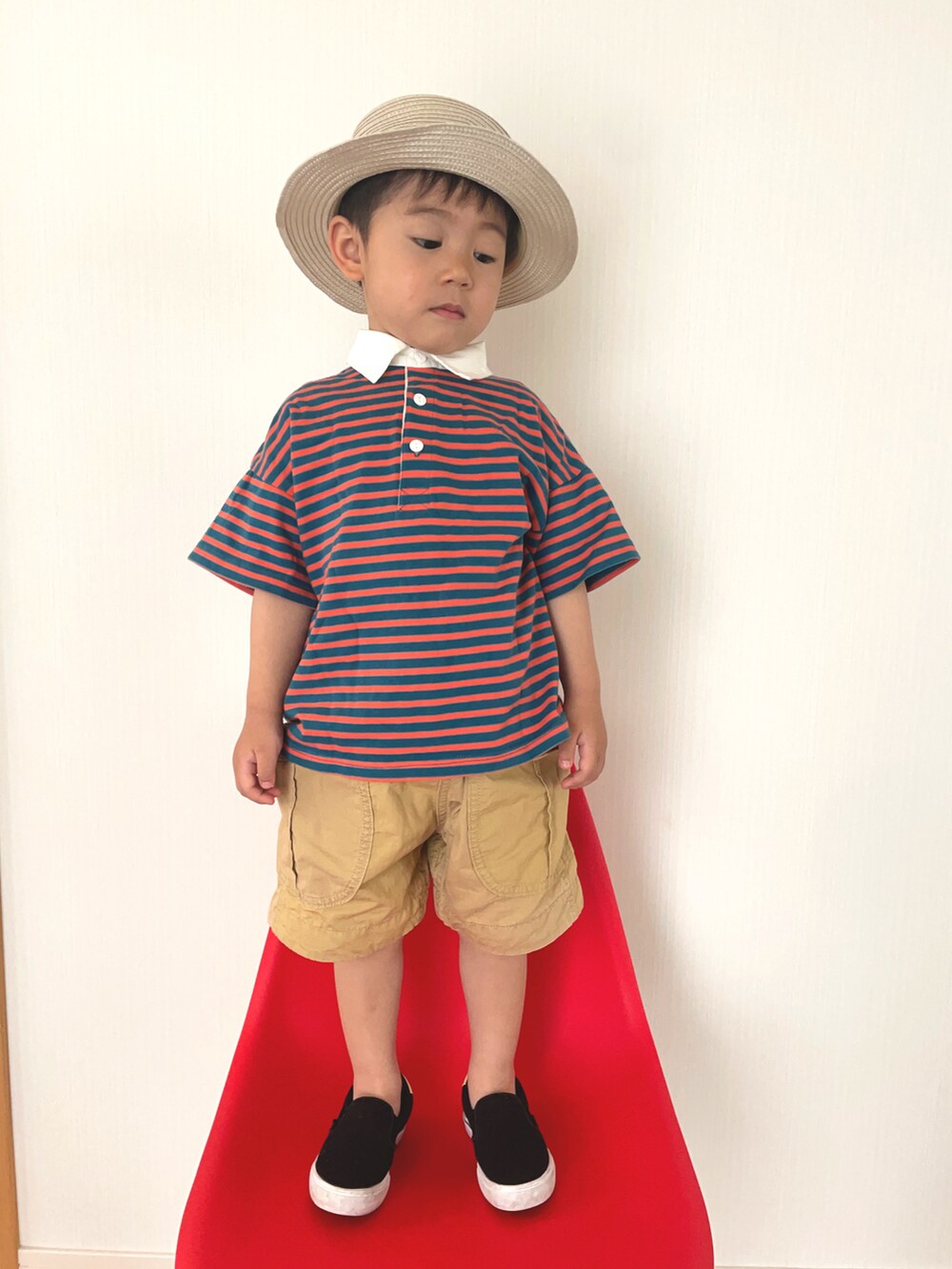 オレンジ系のポロシャツ、ブラック系のスニーカー、ベージュ系のその他パンツを着用したキッズの夏コーディネートの3枚目の写真