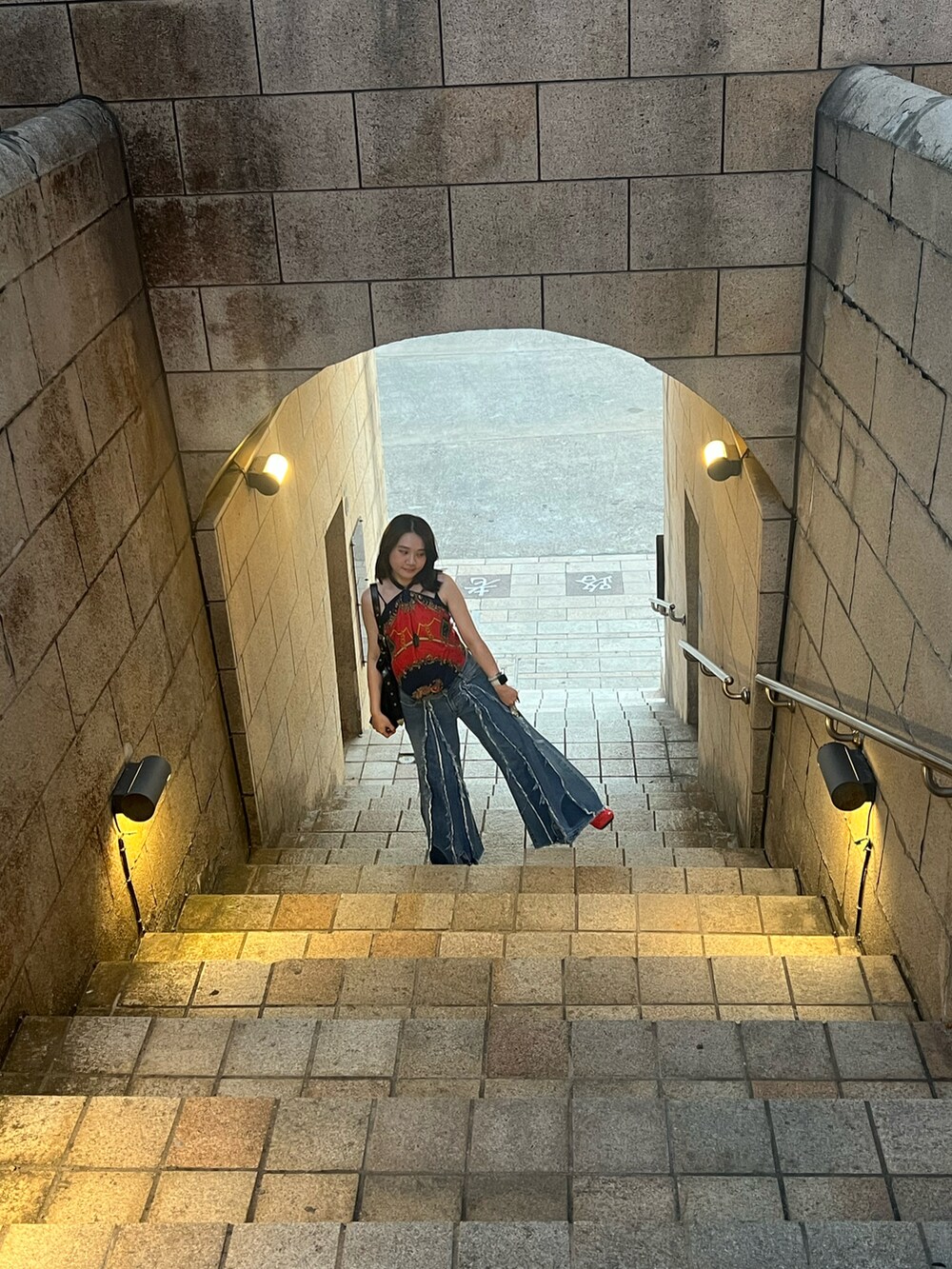 ブルー系のデニムパンツ、レッド系のバレエシューズ、ブラック系のショルダーバッグを着用したレディースの秋コーディネートの2枚目の写真