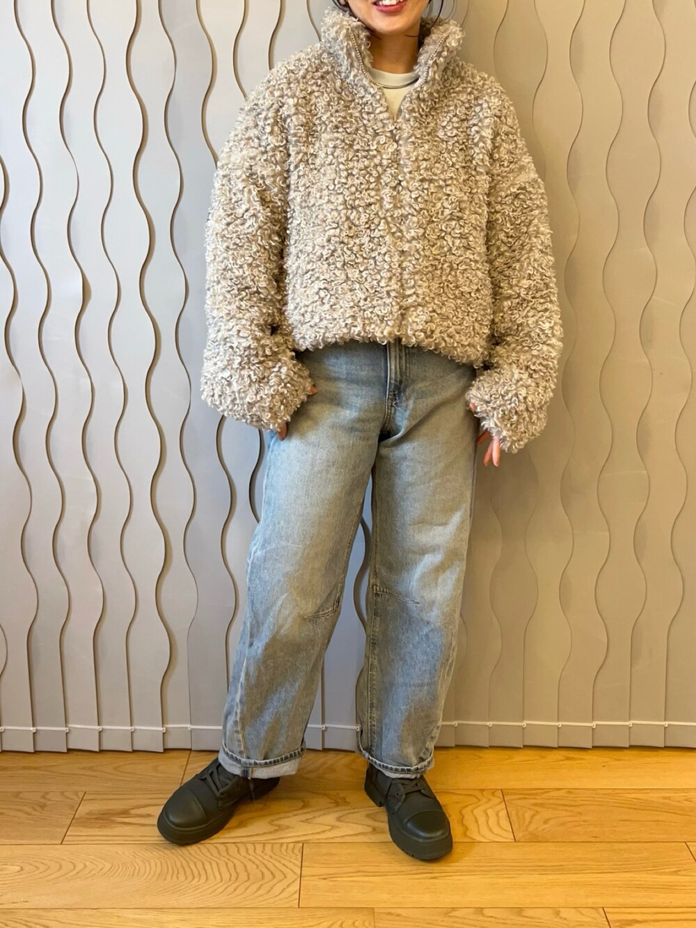 グレー系のブルゾン、ブルー系のデニムパンツ、グリーン系のスニーカーを着用したレディースの秋コーディネートの2枚目の写真