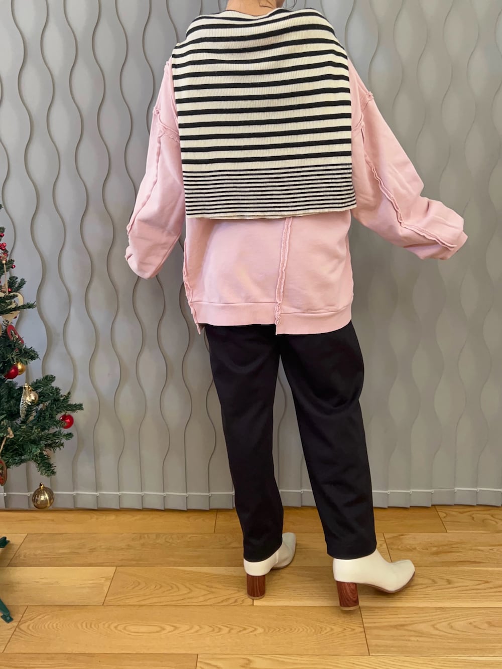 ホワイト系のニット/セーター、ピンク系のスウェット、ブラック系のパンツを着用したレディースの冬コーディネートの2枚目の写真