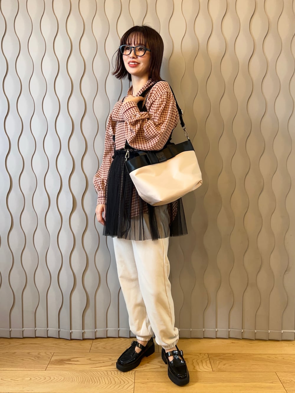 レッド系のシャツ/ブラウス、ブラック系のキャミソール、ベージュ系のトートバッグを着用したレディースの冬コーディネートの2枚目の写真