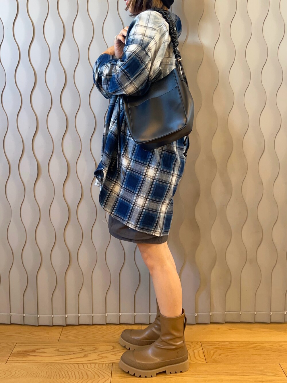 ブルー系のシャツ/ブラウス、ベージュ系のブーツ、ブラック系のショルダーバッグを着用したレディースの秋コーディネートの2枚目の写真