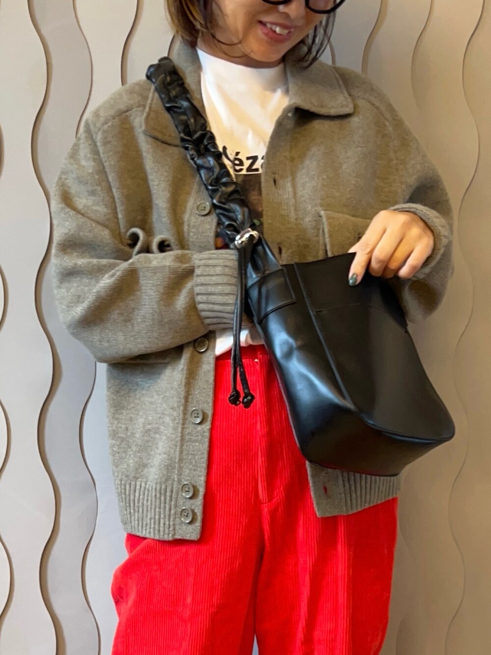 ブラック系のショルダーバッグ、ベージュ系のジャケット/アウター、ブルー系のデニムパンツを着用したレディースの秋コーディネートの2枚目の写真