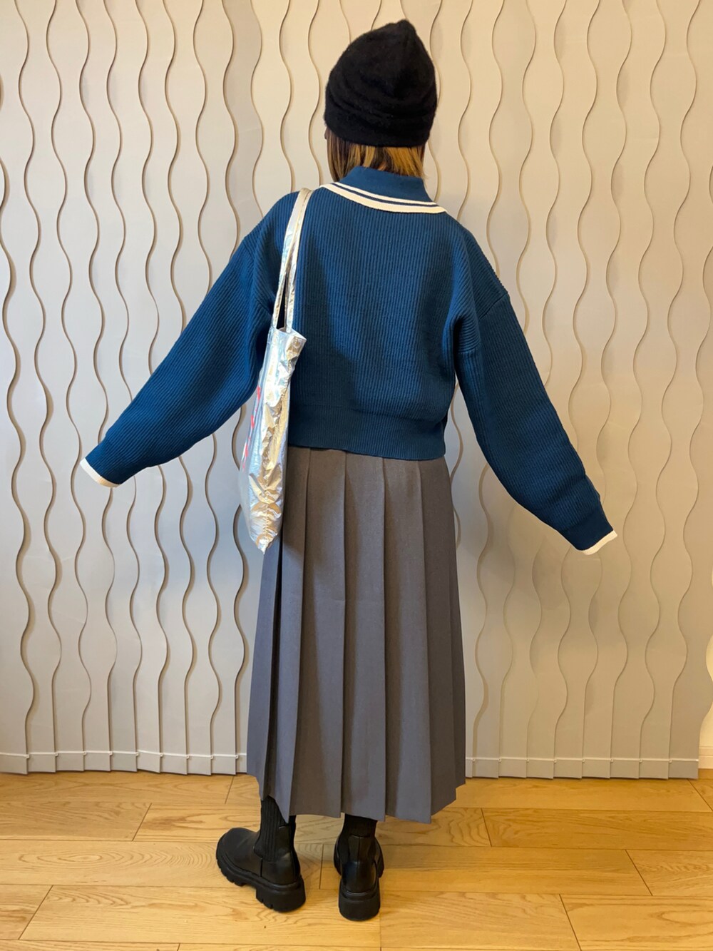 ブルー系のニット/セーター、グレー系のスカート、ブラック系のブーツを着用したレディースの秋コーディネートの2枚目の写真