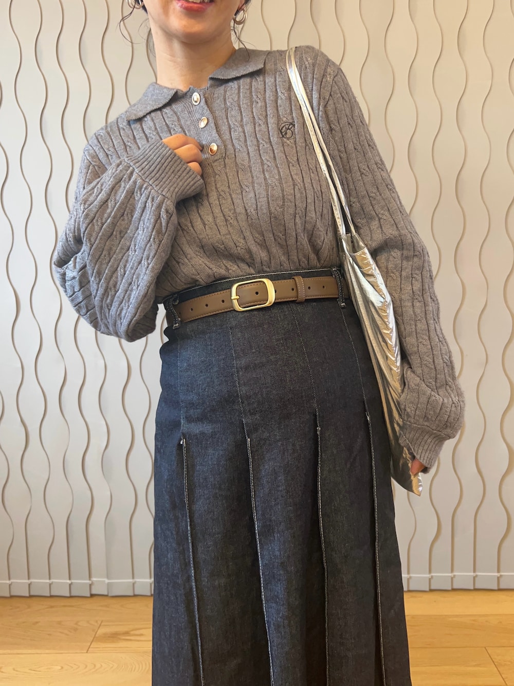 グレー系のニット/セーター、シルバー系のトートバッグ、ブルー系のデニムスカートを着用したレディースの秋コーディネートの3枚目の写真