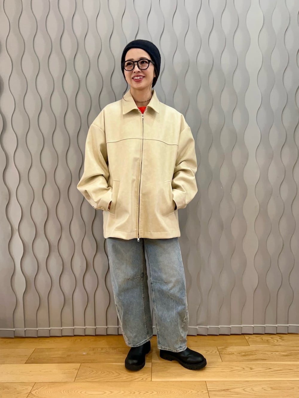 ホワイト系のブルゾン、オレンジ系のスウェット、ブラック系のニットキャップ/ビーニーを着用したレディースの冬コーディネートの2枚目の写真