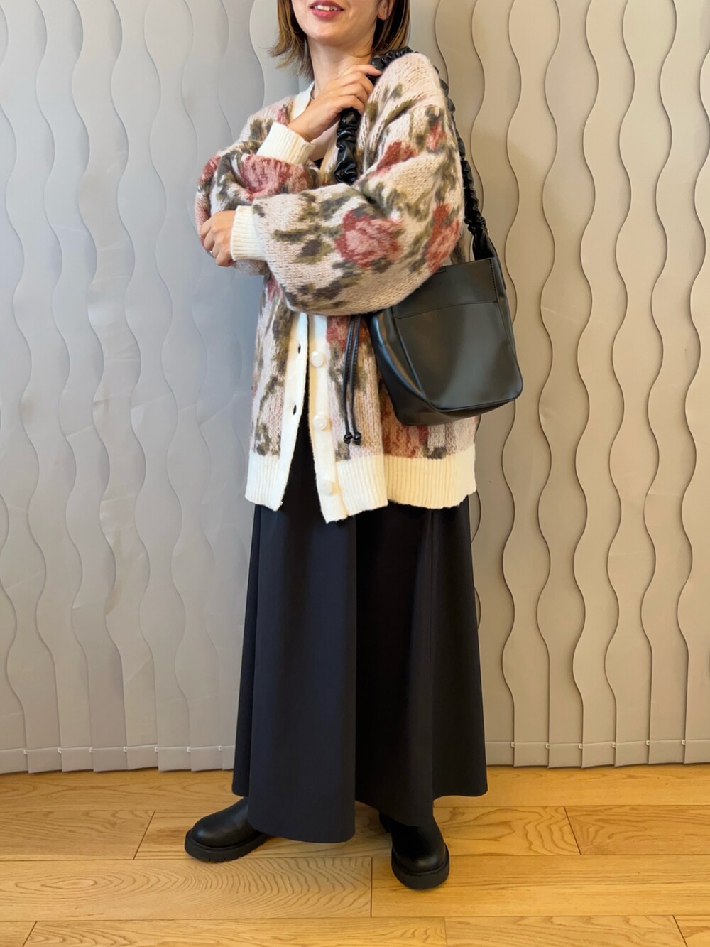 ホワイト系のカーディガン/ボレロ、ブラック系のショルダーバッグ、ブラック系のブーツを着用したレディースの秋コーディネートの2枚目の写真