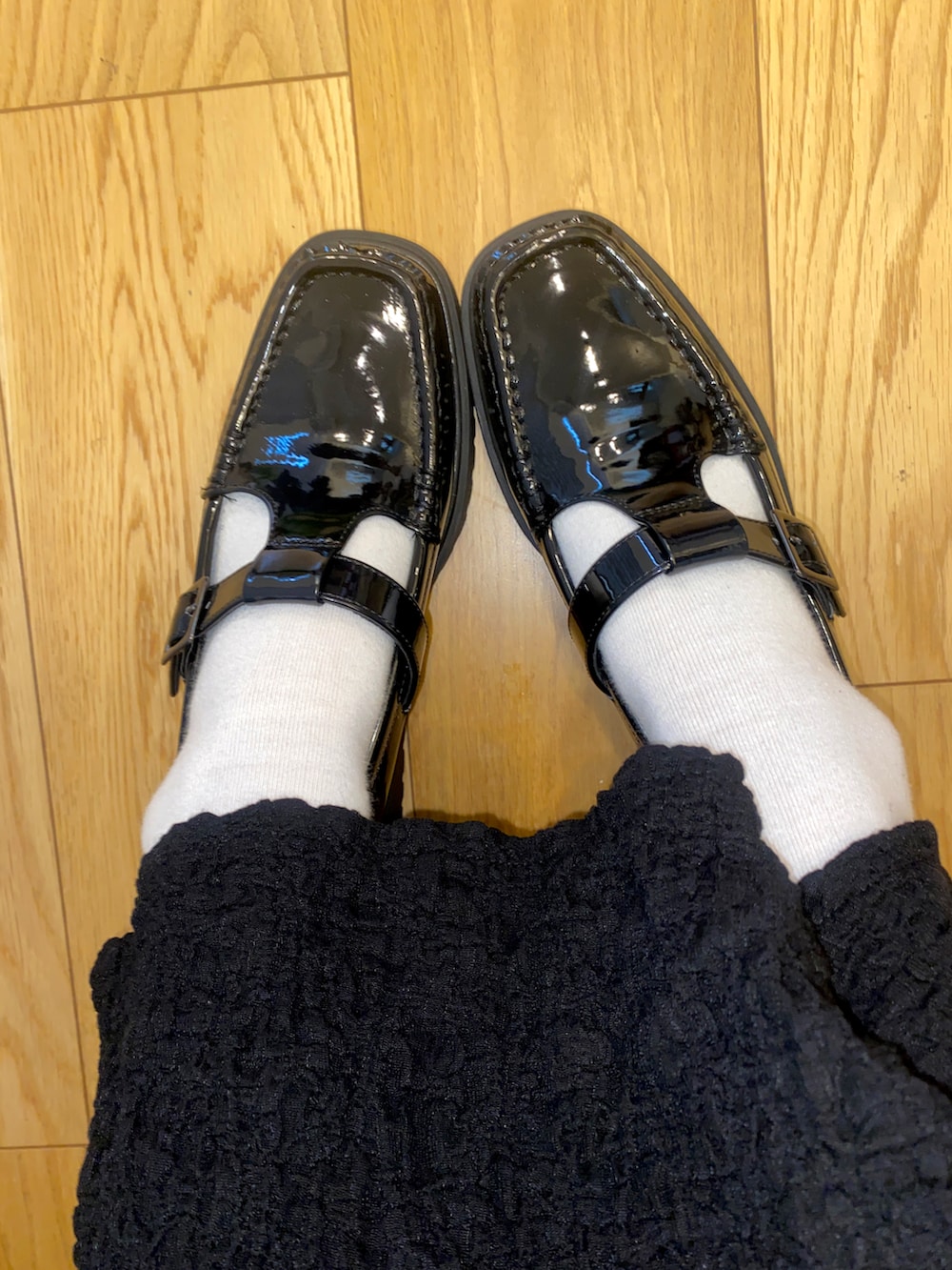 パープル系のカーディガン/ボレロ、ブラック系のワンピース、ブラック系のパンプスを着用したレディースの春コーディネートの2枚目の写真