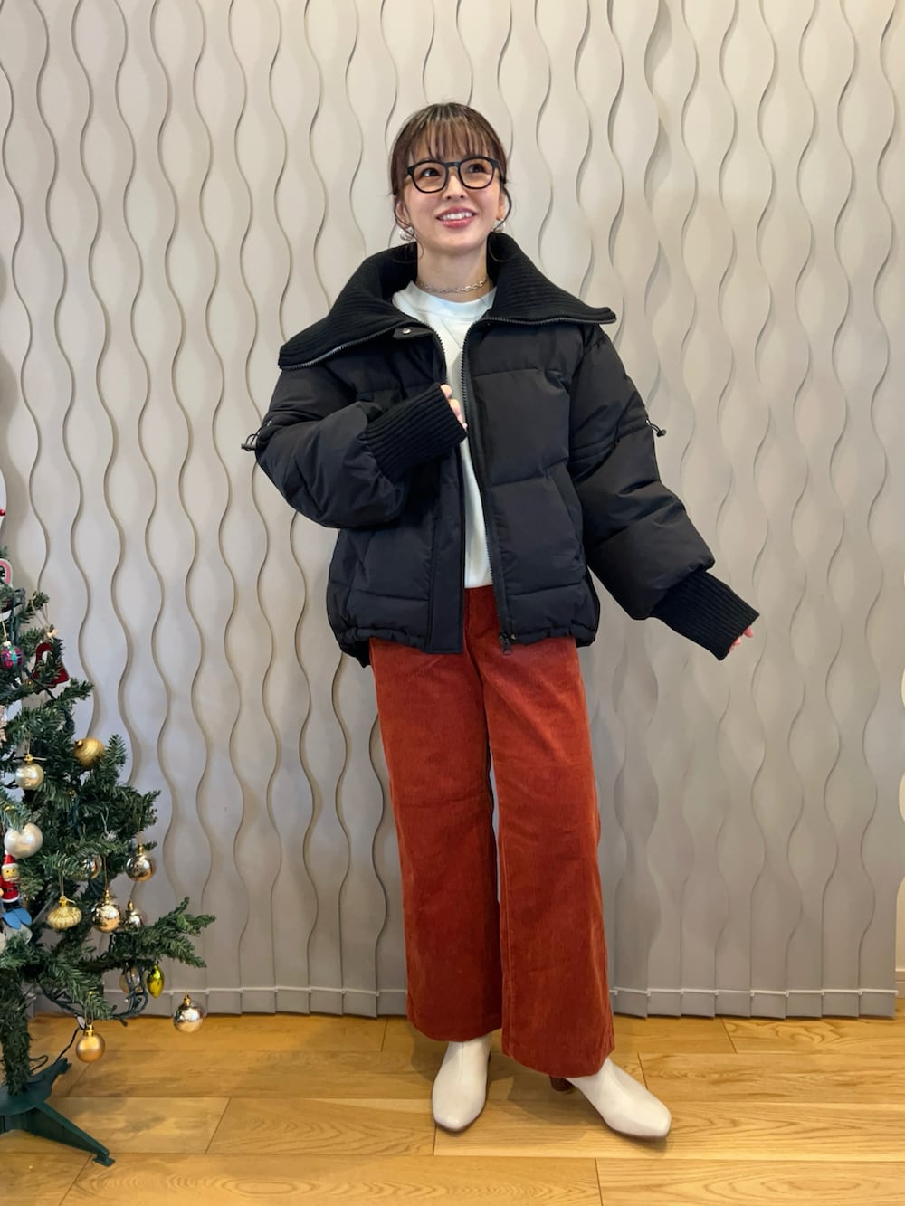 ブラック系のダウンジャケット/コート、オレンジ系のパンツ、ホワイト系のブーツを着用したレディースの冬コーディネートの2枚目の写真