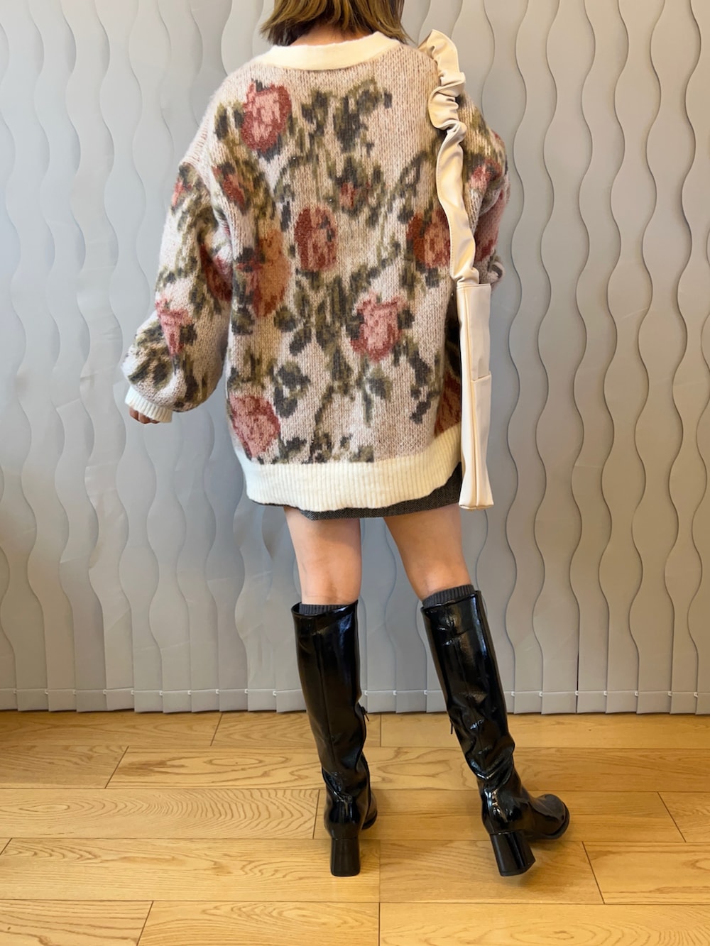 ホワイト系のカーディガン/ボレロ、グレー系のスカート、ブラック系のブーツを着用したレディースの秋コーディネートの2枚目の写真