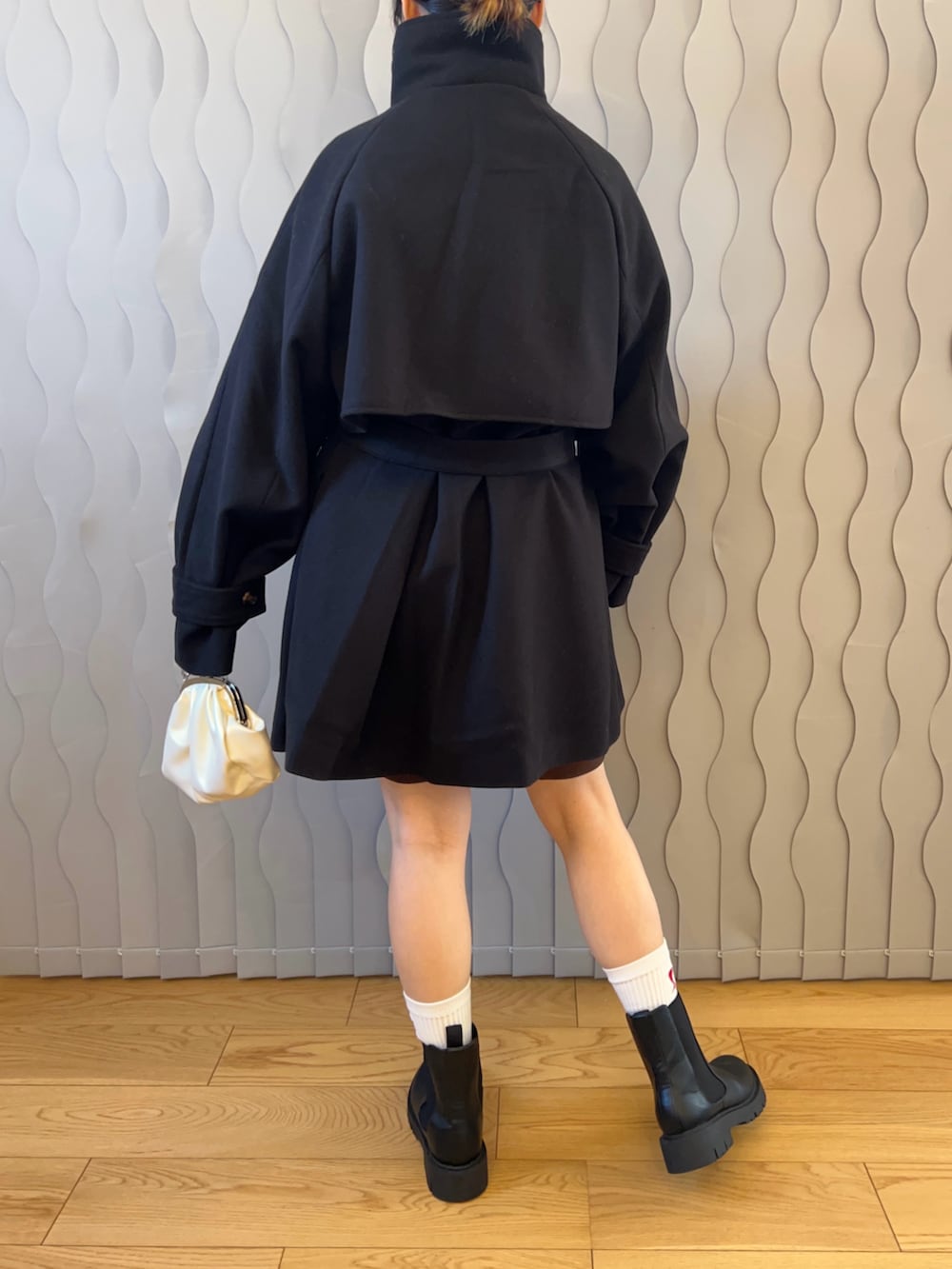 ブラック系のトレンチコート、ブラック系のブーツ、ホワイト系のハンドバッグを着用したレディースの秋コーディネートの2枚目の写真