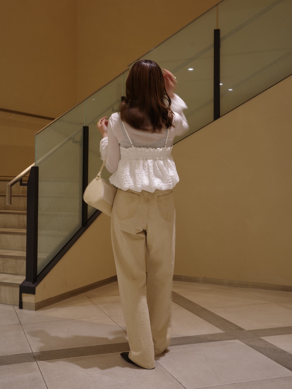 ブラック系のパンプス、ホワイト系のシャツ/ブラウス、ベージュ系のショルダーバッグを着用したレディースの春コーディネートの2枚目の写真