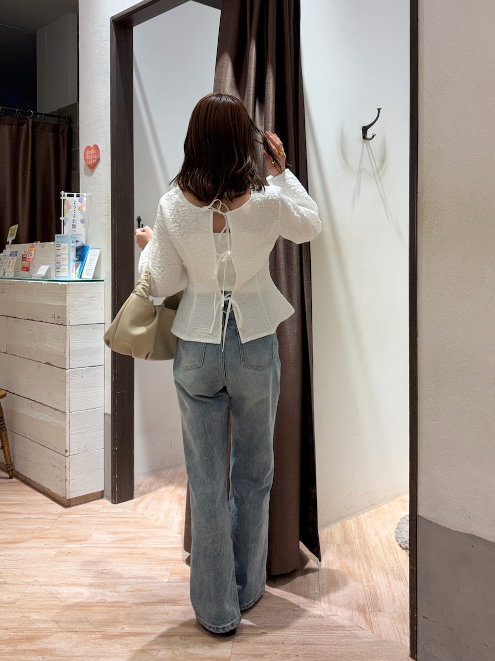 ブルー系のデニムパンツ、ブラック系のパンプス、ベージュ系のショルダーバッグを着用したレディースの春コーディネートの2枚目の写真