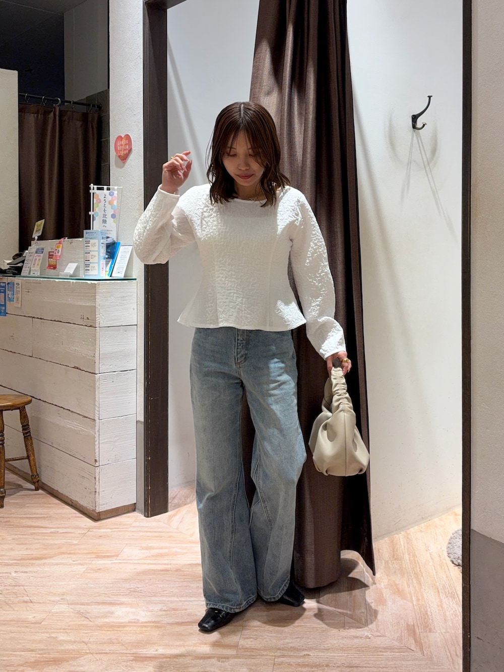 ブルー系のデニムパンツ、ブラック系のパンプス、ベージュ系のショルダーバッグを着用したレディースの春コーディネートの6枚目の写真