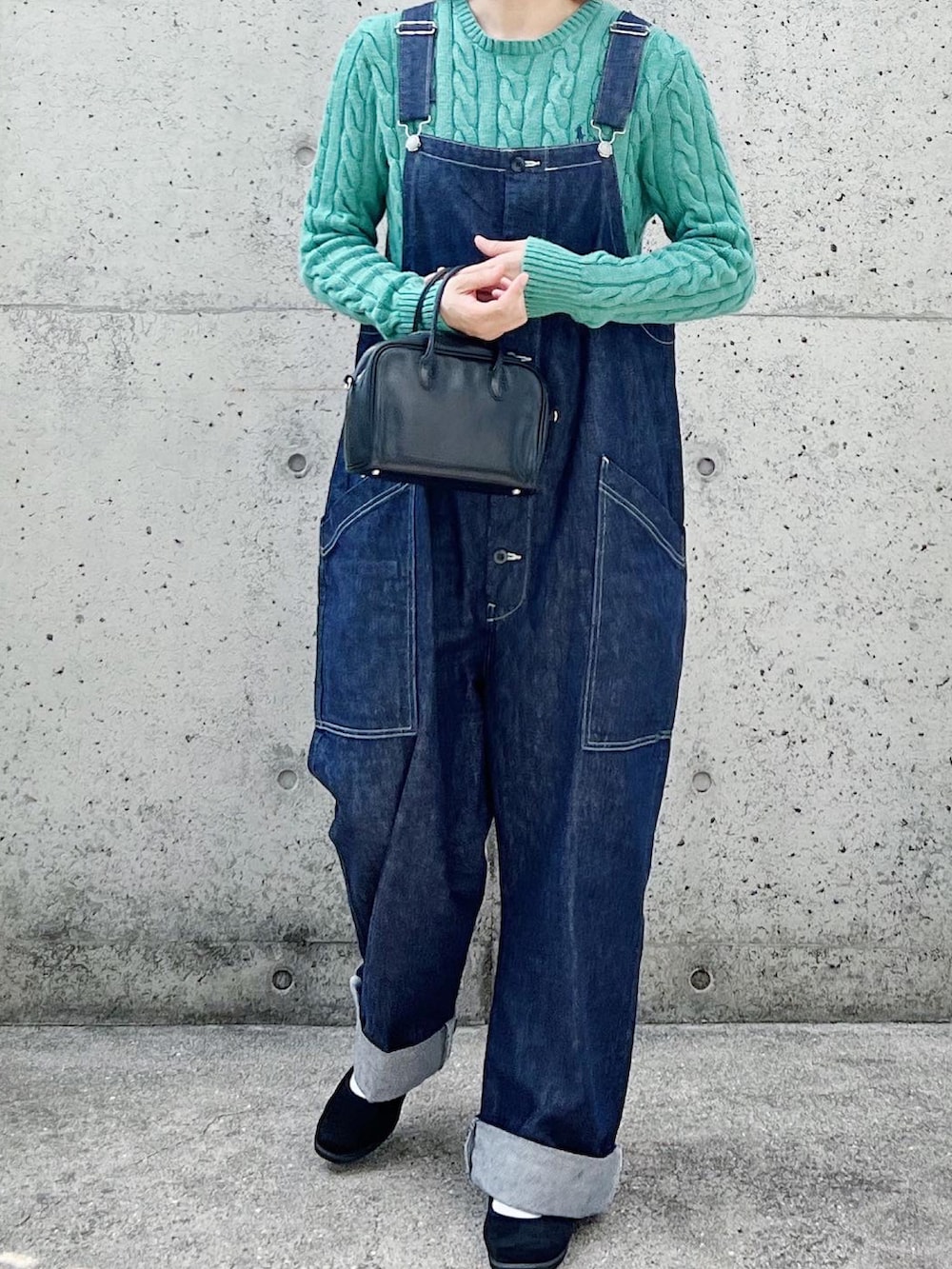 ブルー系のサロペット/オーバーオール、ブラック系のスリッポン、グリーン系のニット/セーターを着用したレディースの秋コーディネートの2枚目の写真