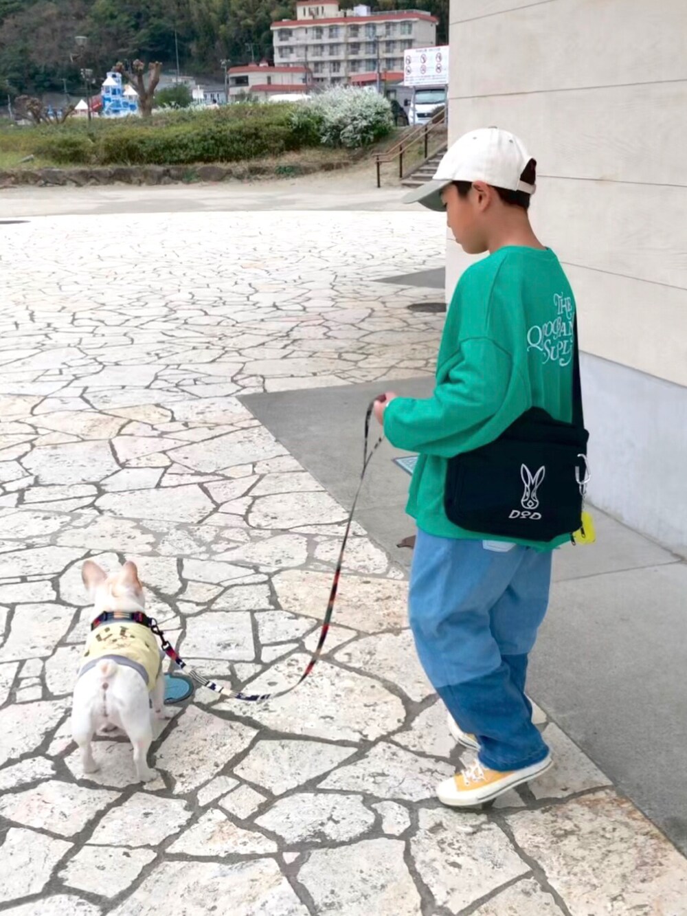 グリーン系のスウェット、ブルー系のデニムパンツ、ブラック系のショルダーバッグを着用したキッズの春コーディネートの3枚目の写真
