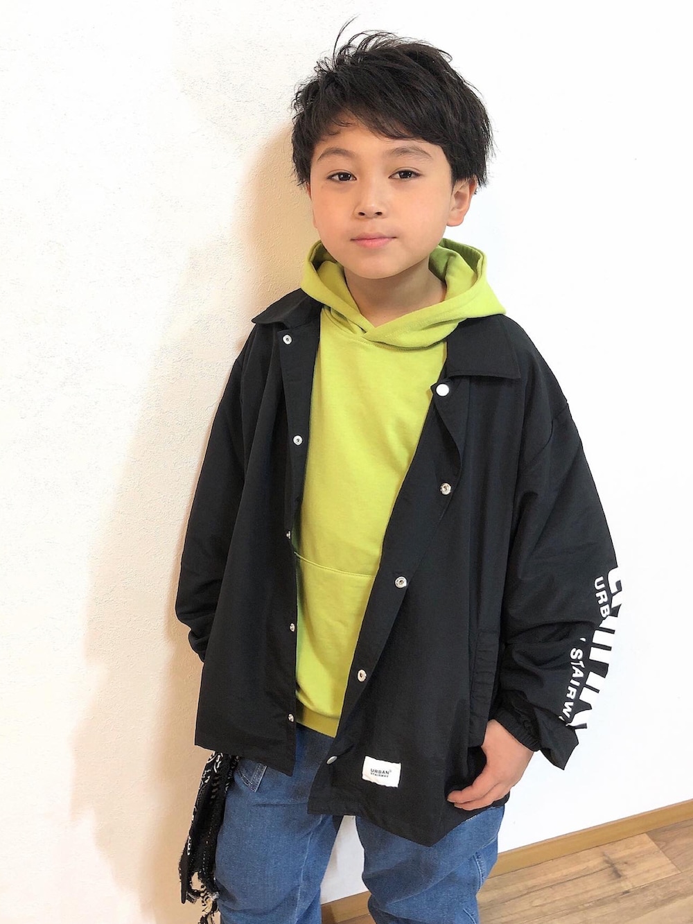 ブラック系のノーカラージャケット、グリーン系のパーカー、ブルー系のデニムパンツを着用したキッズの春コーディネートの3枚目の写真