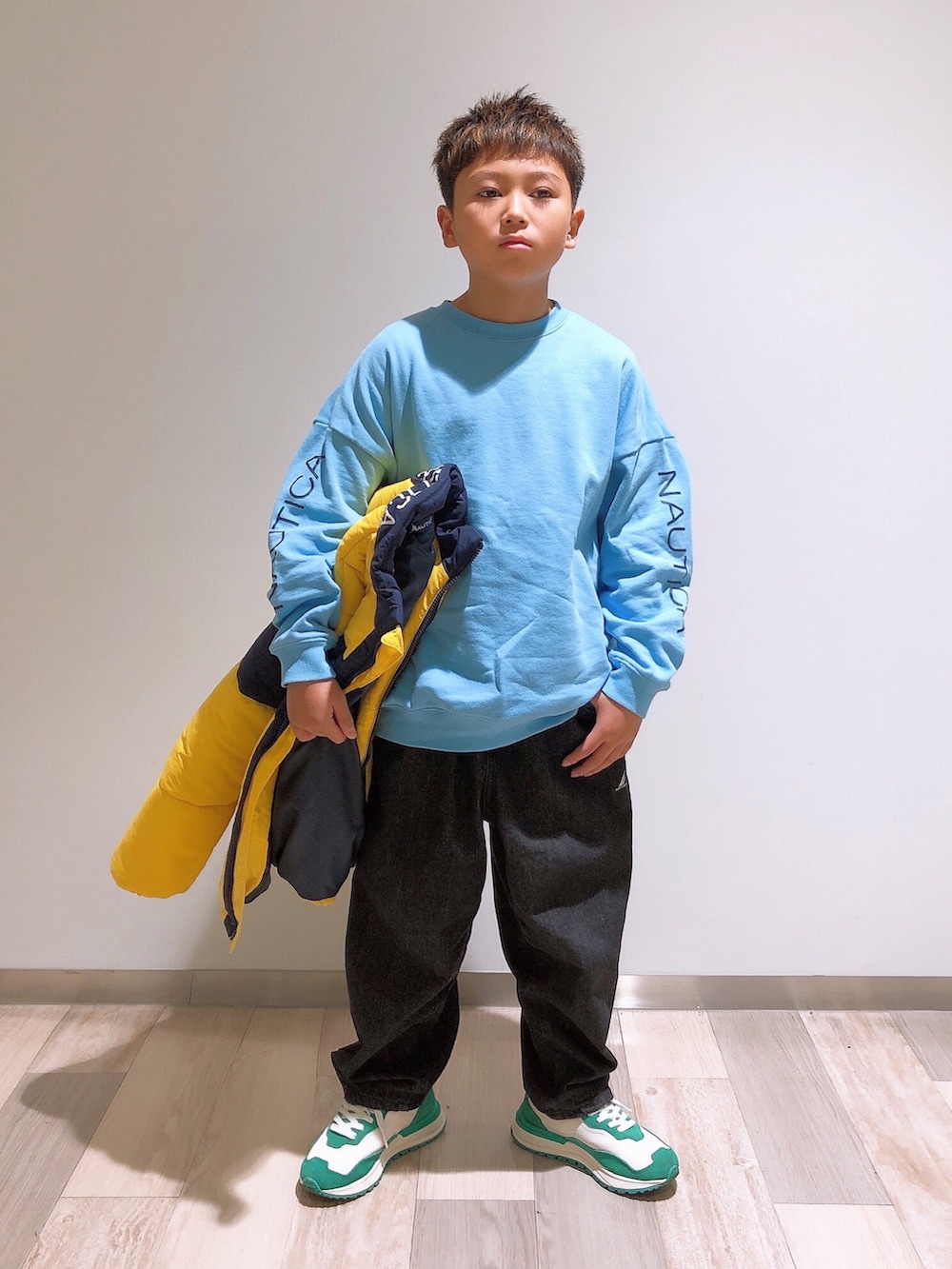 イエロー系のブルゾン、ブルー系のスウェット、ブラック系のデニムパンツを着用したキッズの冬コーディネートの2枚目の写真