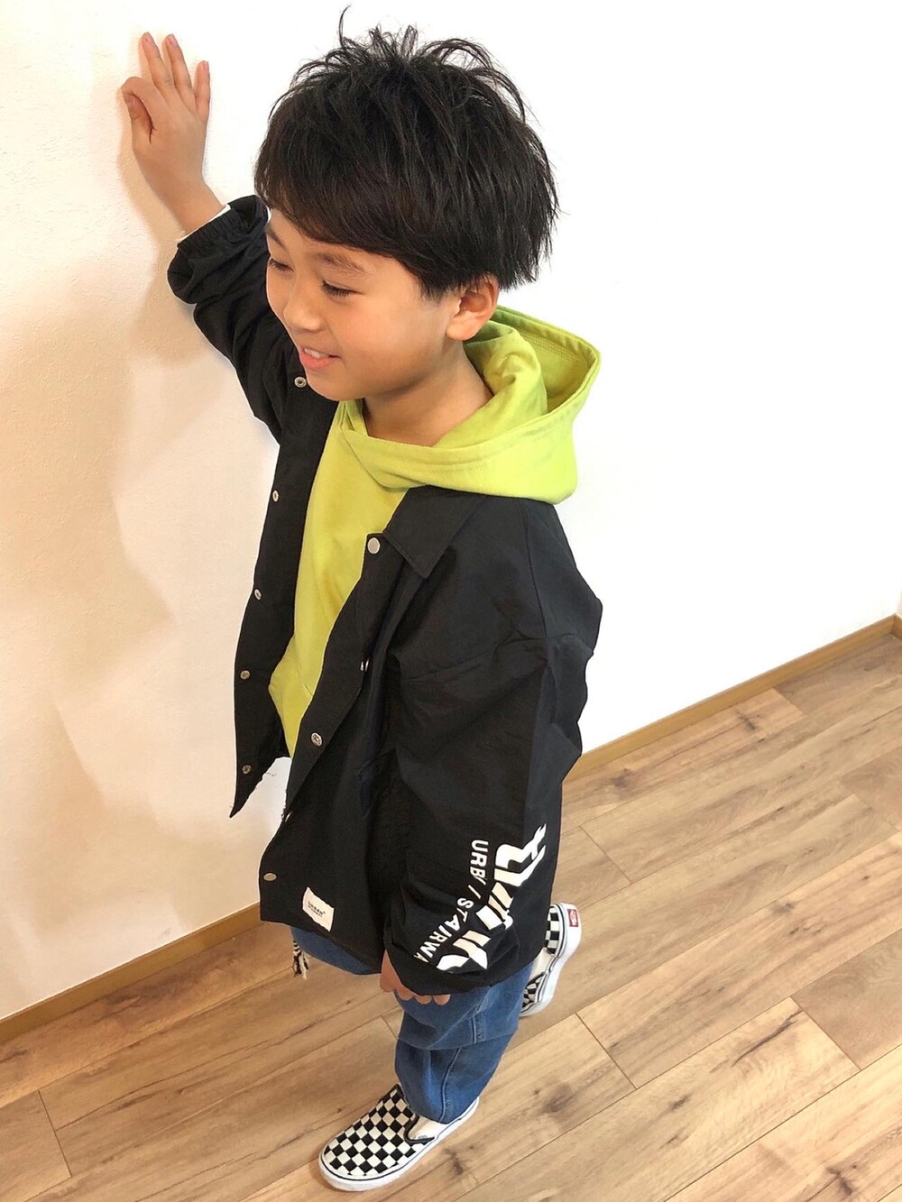ブラック系のノーカラージャケット、グリーン系のパーカー、ブルー系のデニムパンツを着用したキッズの春コーディネートの4枚目の写真