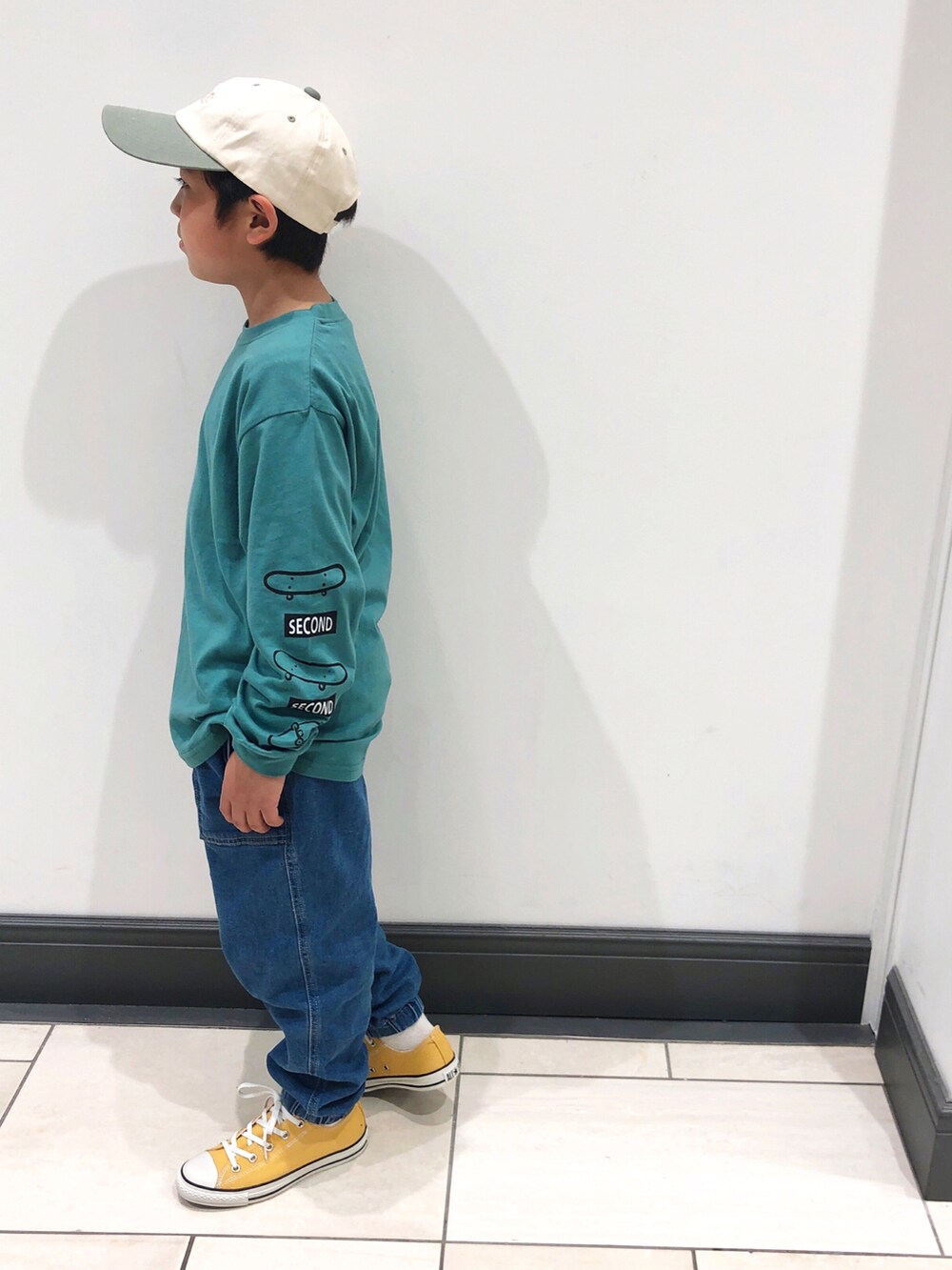 グリーン系のTシャツ/カットソー、ブルー系のデニムパンツ、イエロー系のスニーカーを着用したキッズの春コーディネートの2枚目の写真