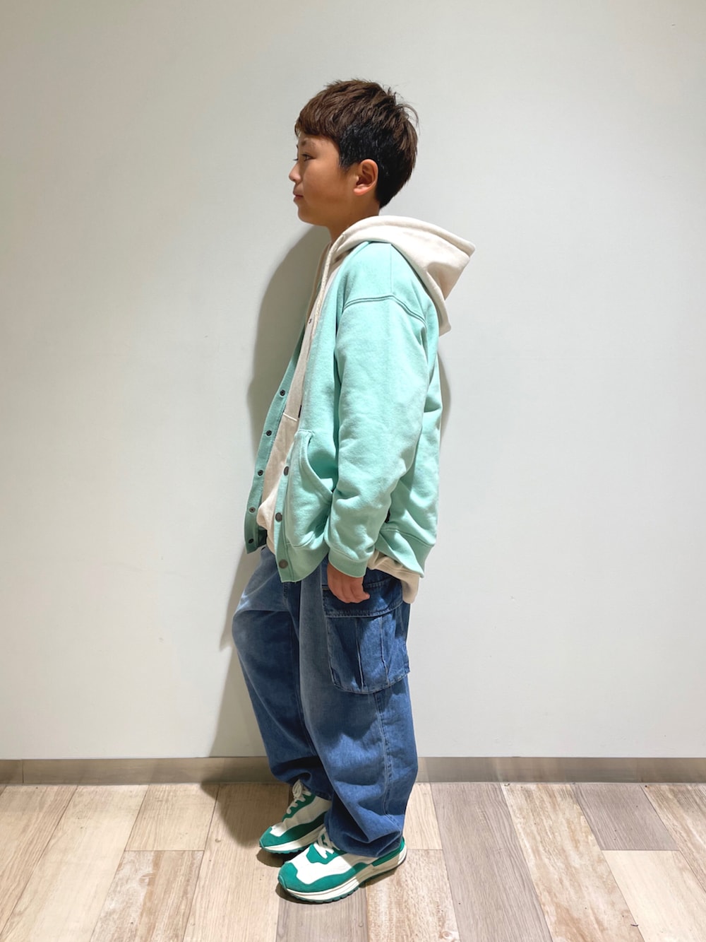 グリーン系のカーディガン/ボレロ、ホワイト系のパーカー、ブルー系のデニムパンツを着用したキッズの春コーディネートの2枚目の写真