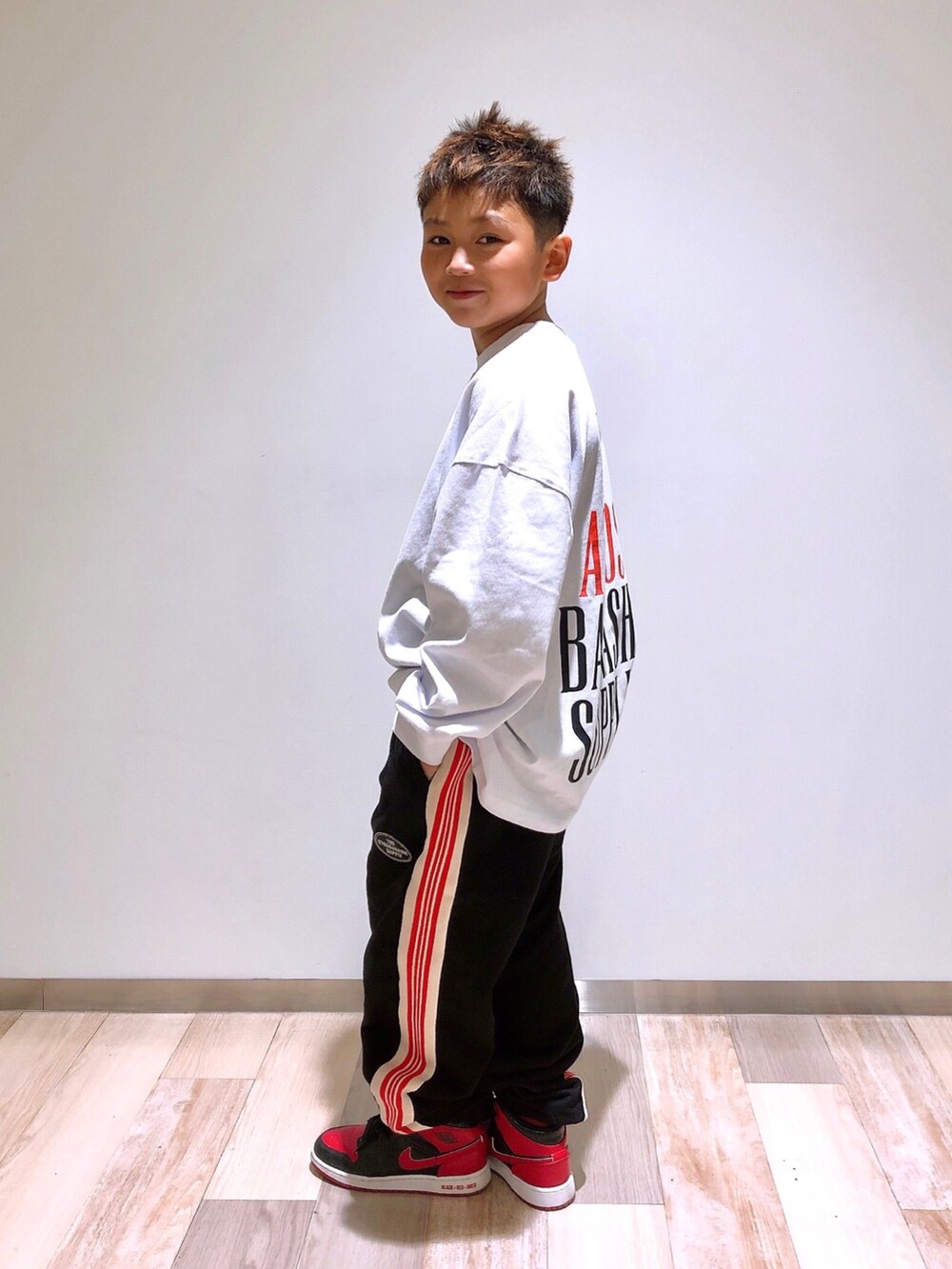 ホワイト系のTシャツ/カットソー、ブラック系のスウェットパンツ、ブラック系のスニーカーを着用したキッズの冬コーディネートの2枚目の写真