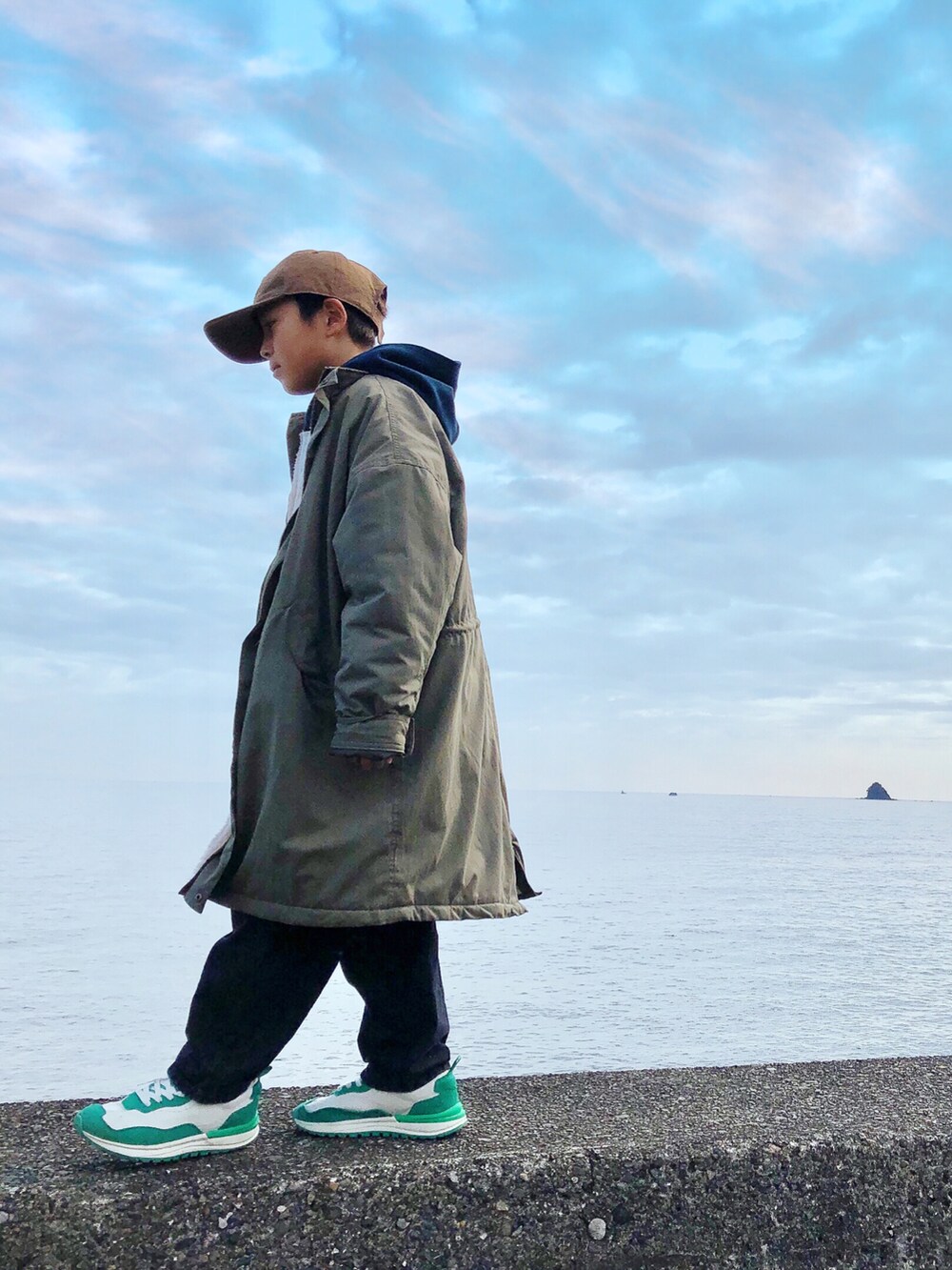 グリーン系のモッズコート、ホワイト系のパーカー、ブラック系のデニムパンツを着用したキッズの冬コーディネートの3枚目の写真