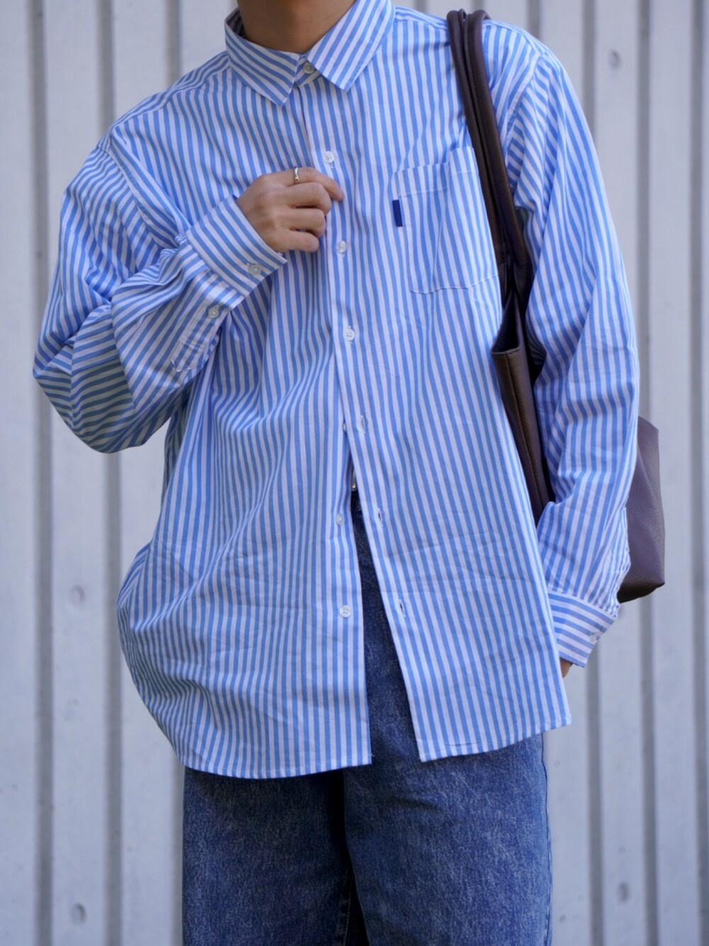 ブルー系のシャツ/ブラウス、ブルー系のデニムパンツ、ブラウン系のトートバッグを着用したメンズの春コーディネートの4枚目の写真