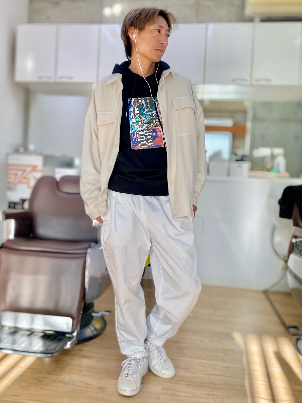 ホワイト系のチノパンツ、ブラック系のパーカー、ホワイト系のカバーオールを着用したメンズの冬コーディネートの2枚目の写真