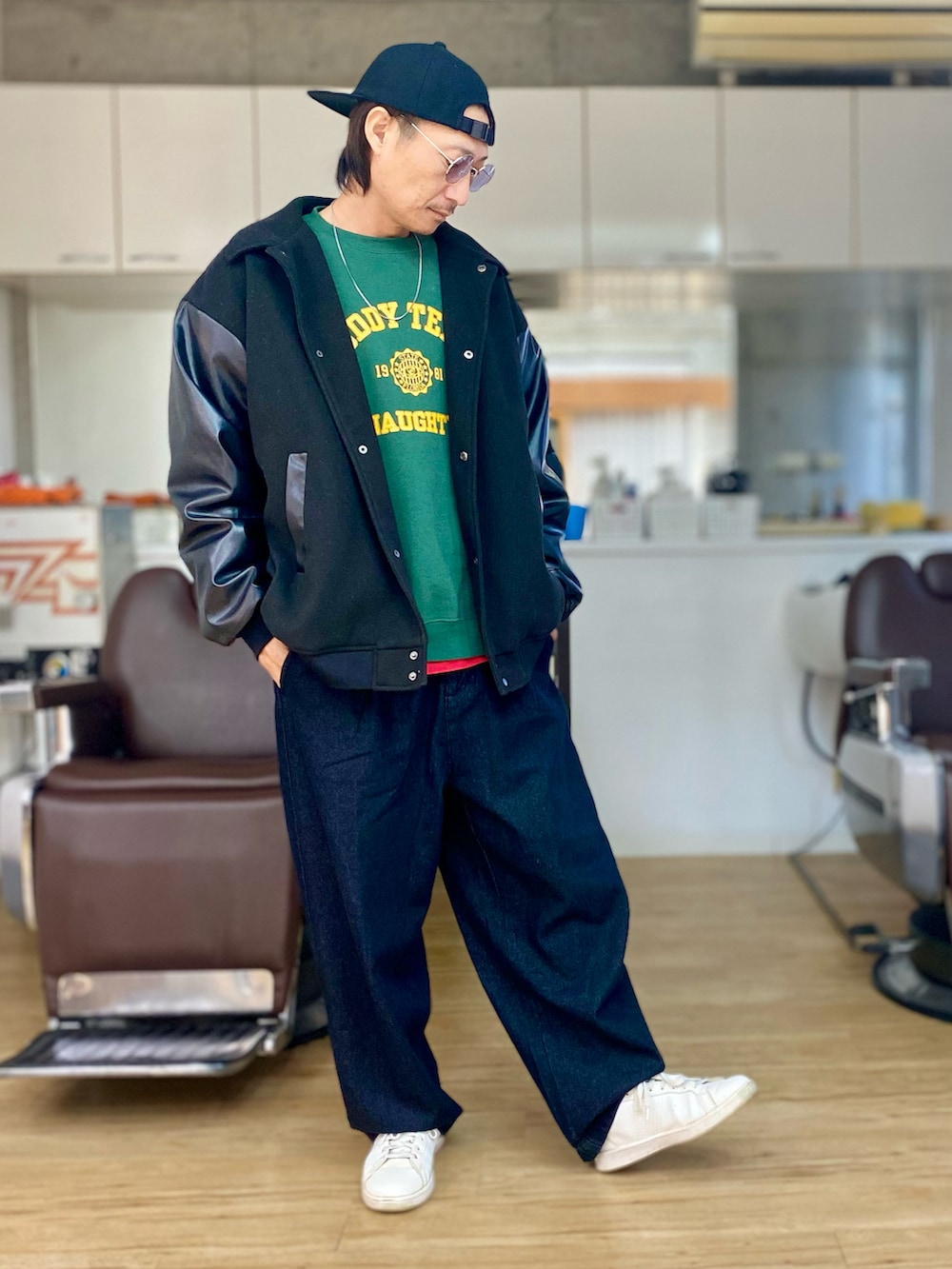 グリーン系のスウェット、ブラック系のスタジャン、ブラック系のデニムパンツを着用したメンズの冬コーディネートの2枚目の写真