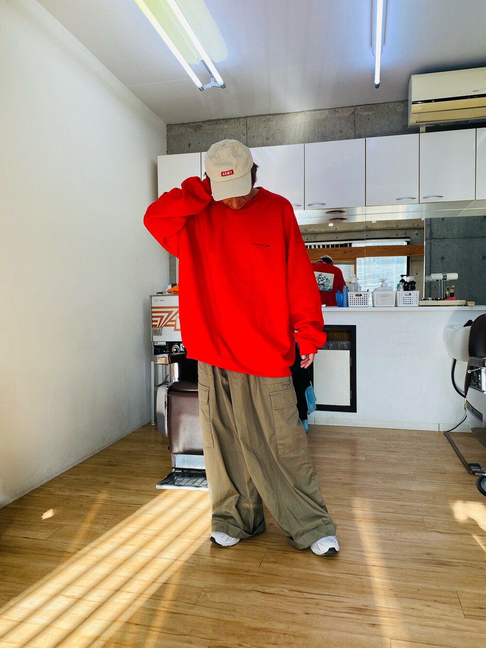 グリーン系のカーゴパンツ、レッド系のスウェット、ホワイト系のスニーカーを着用したメンズの冬コーディネートの3枚目の写真